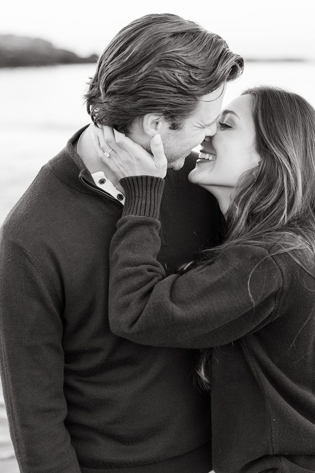 Couple standing on rocks overlooking the ocean during Maine engagement session at Kettle Cove