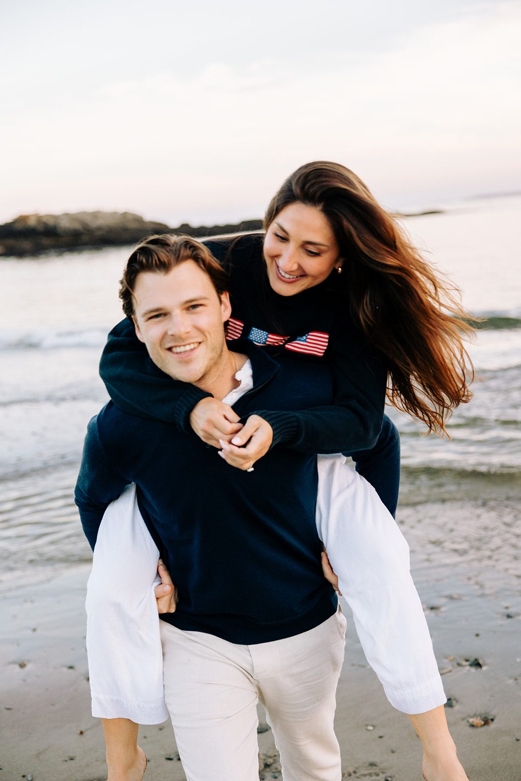 Candid engagement moment of couple laughing by the ocean at Kettle Cove Maine