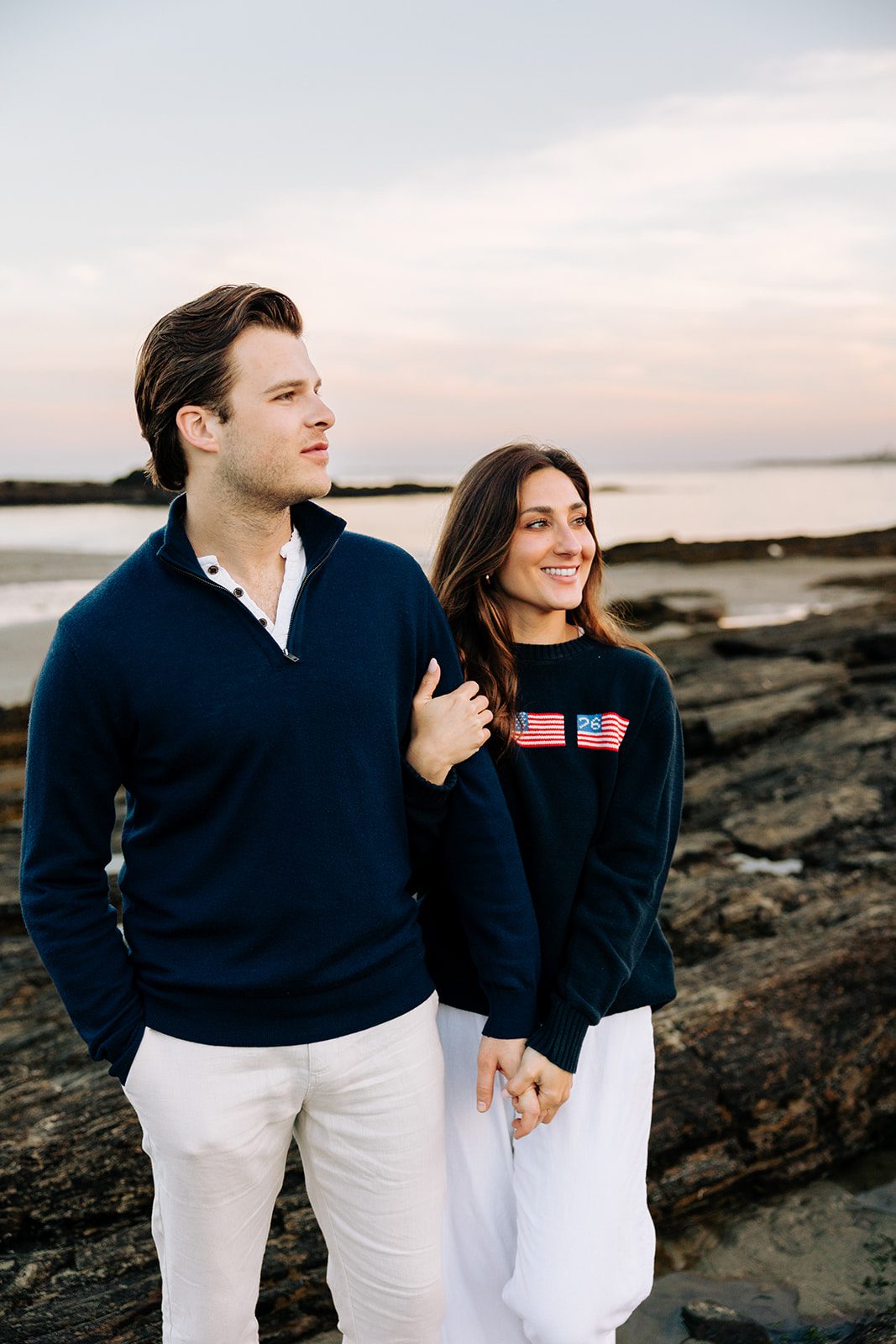 Romantic engagement photo of couple embracing on coastal rocks in Cape Elizabeth Maine at Kettle Cove, candid shot 