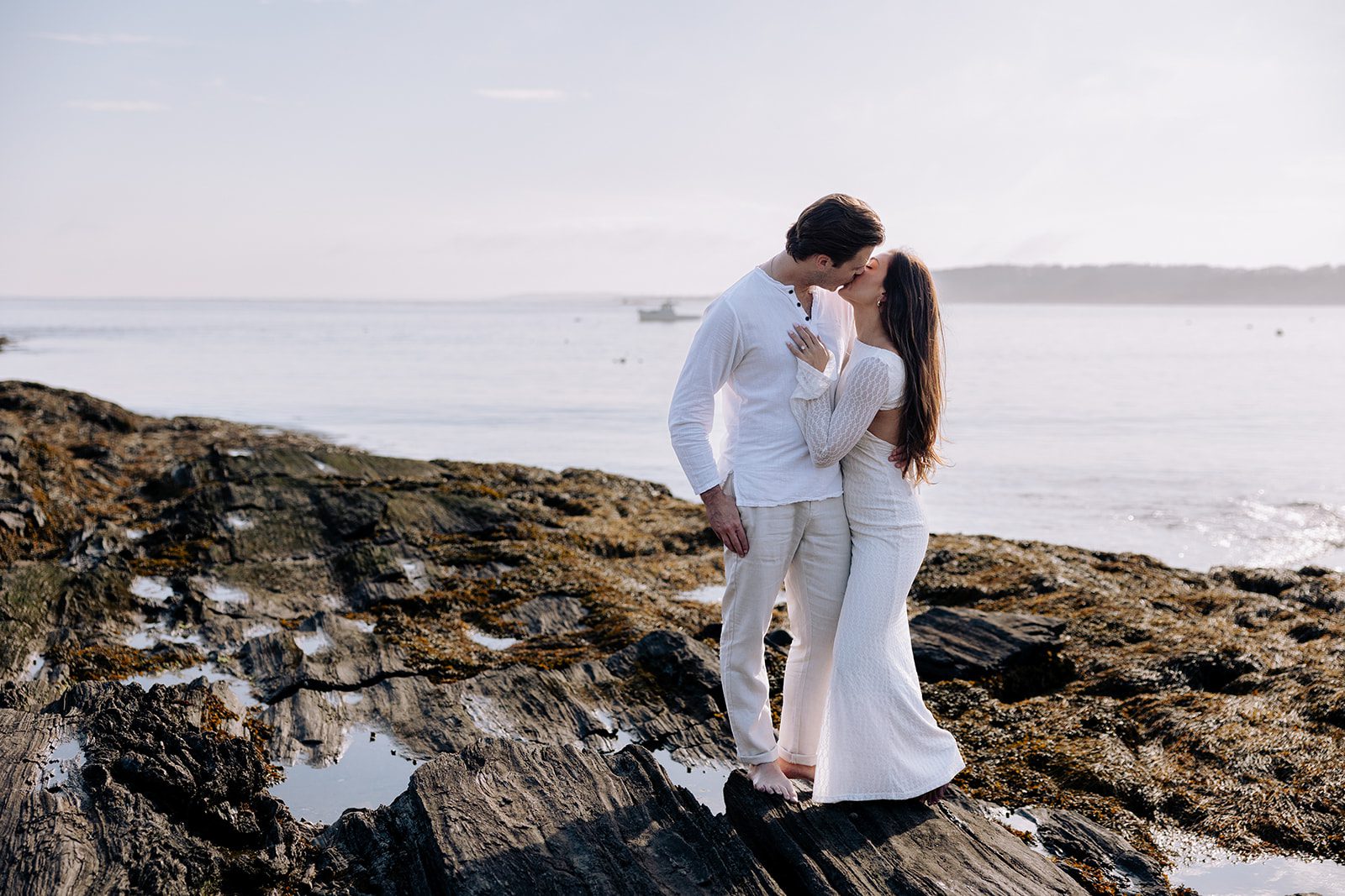 Sweet engagement moment captured on rocky beach in Cape Elizabeth Maine at Kettle Cove